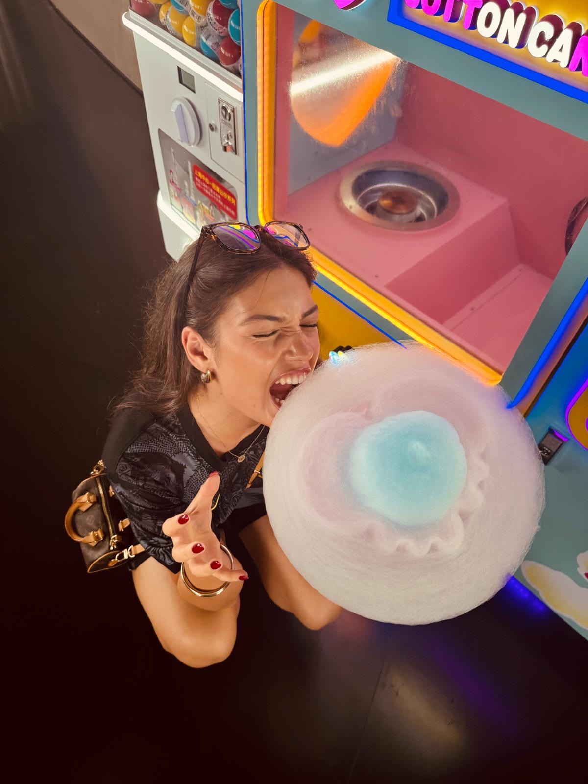 Junge Frau genießt frische Zuckerwatte aus einem Vollautomaten